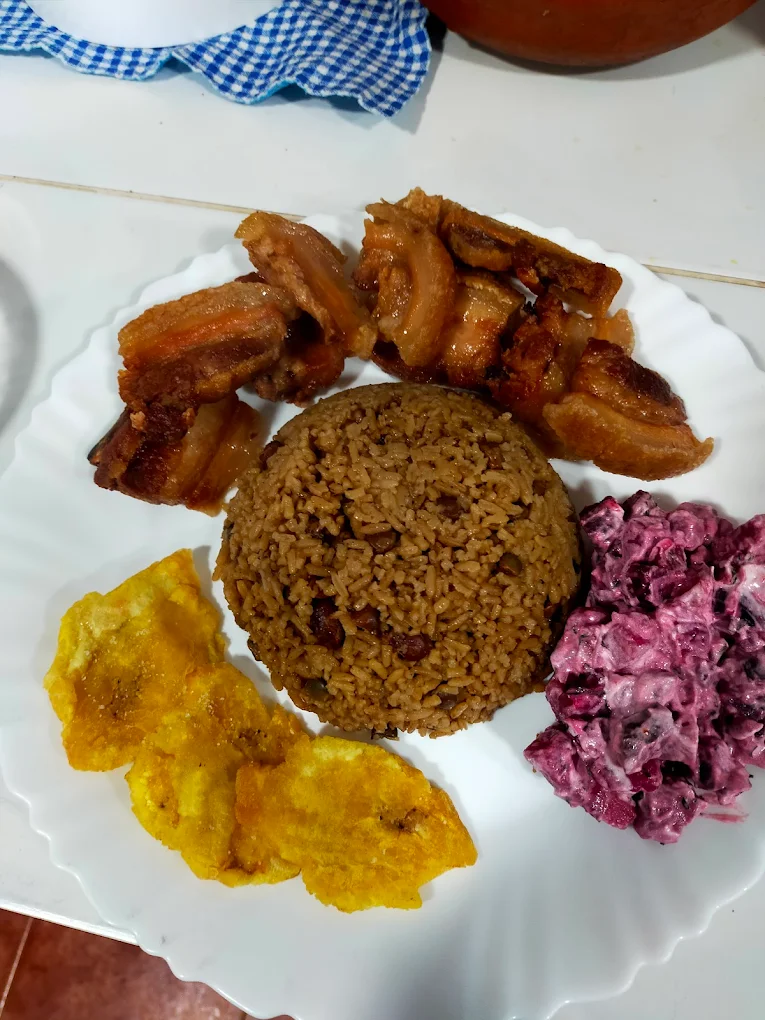 Locrio dominicano de arroz con chicharron y ensaladilla rusa adornado con patacones.
